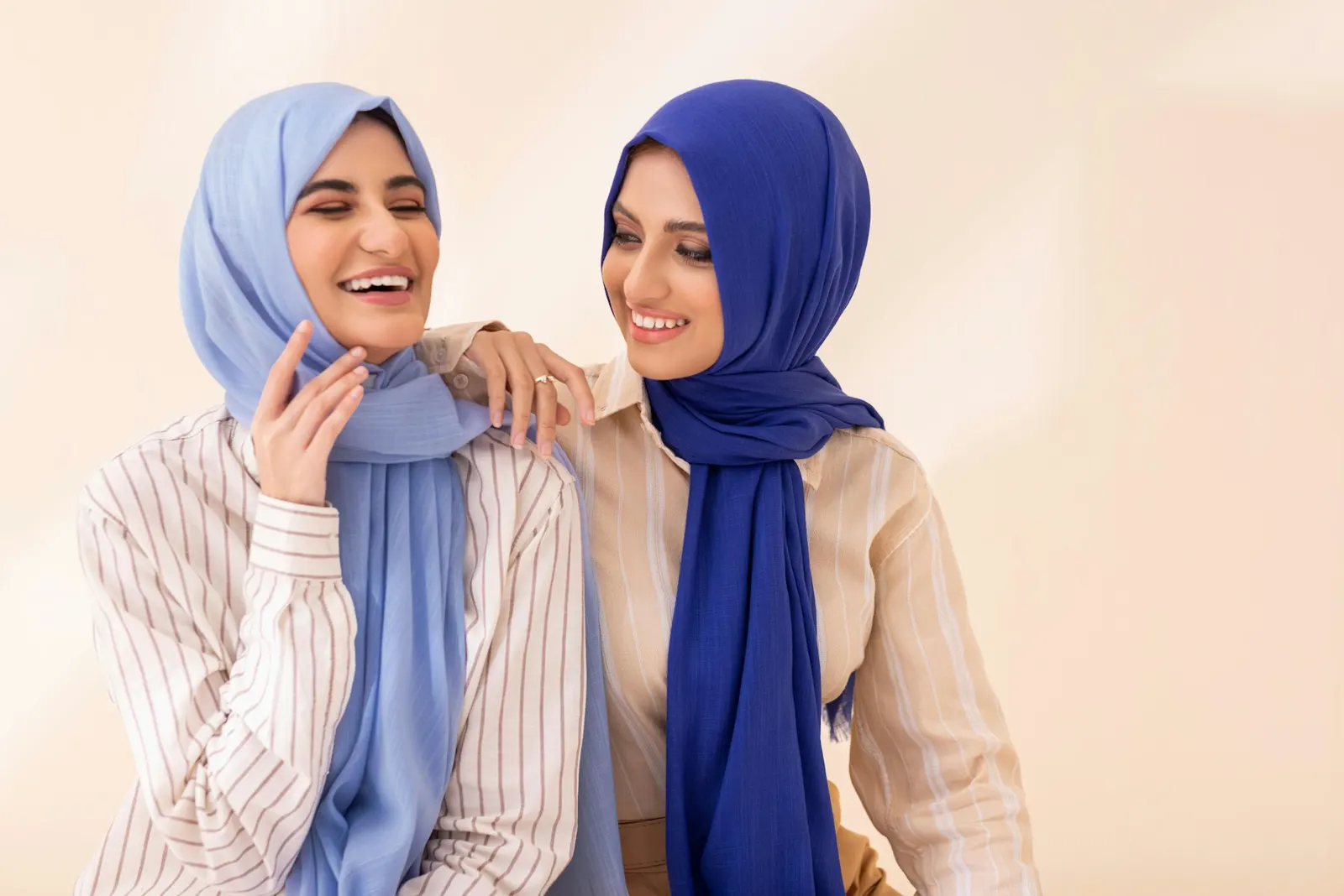 Two friends in sky and cobalt hijabs laughing