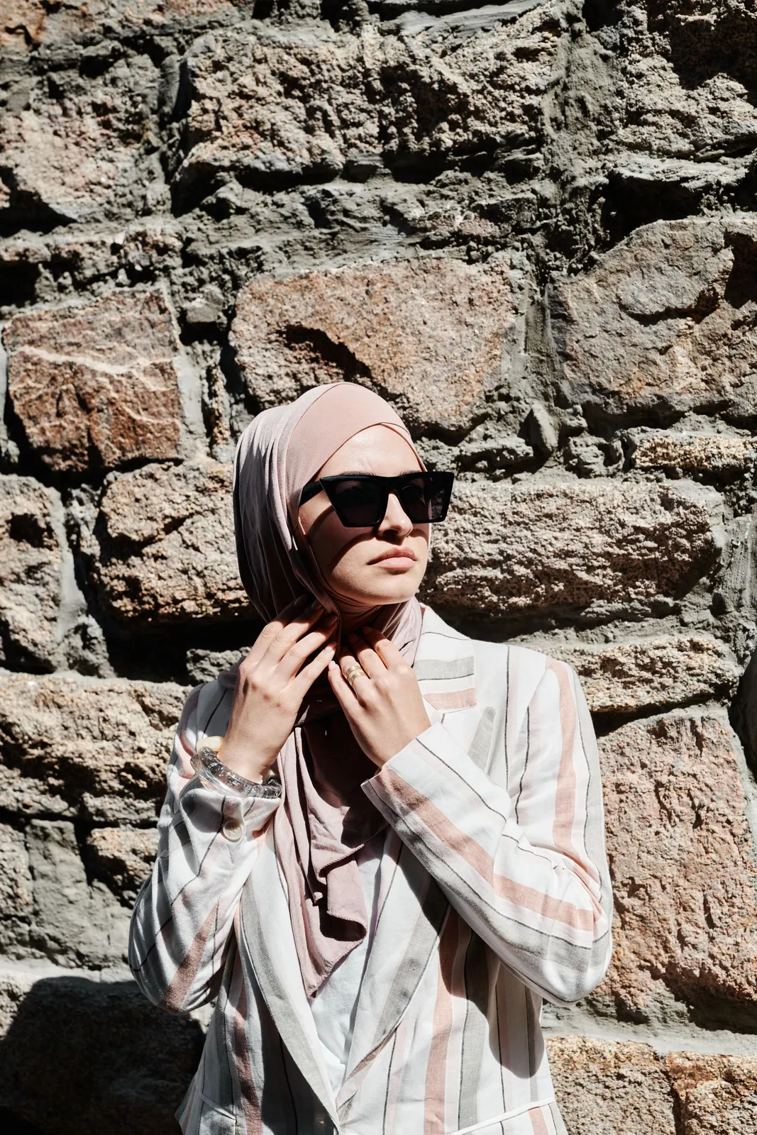 Blush hijab against a sunlit stone wall